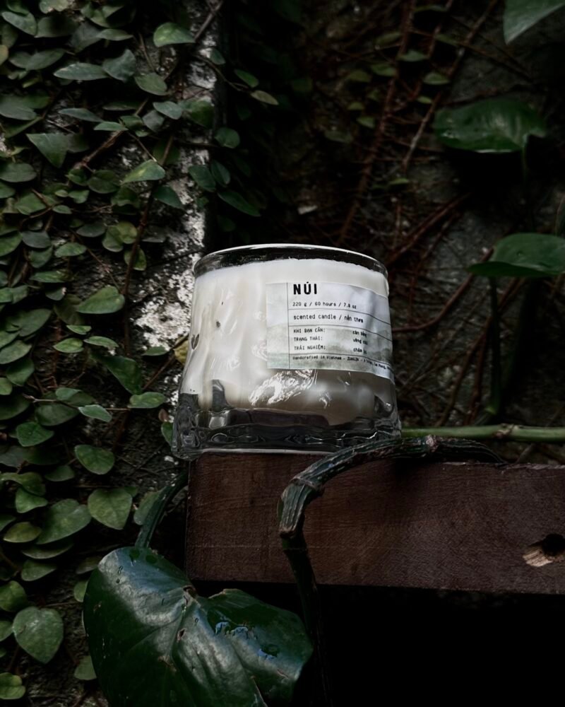 A ZUNGZA glass candle jar among green leaves — A calm day of trekking usually begins the evening before