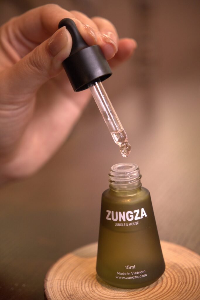 Chai tinh dầu ZUNGZA đặt giữa khung cảnh thiên nhiên - Tiêu đen, hoắc hương và bergamot trong một mùi hương