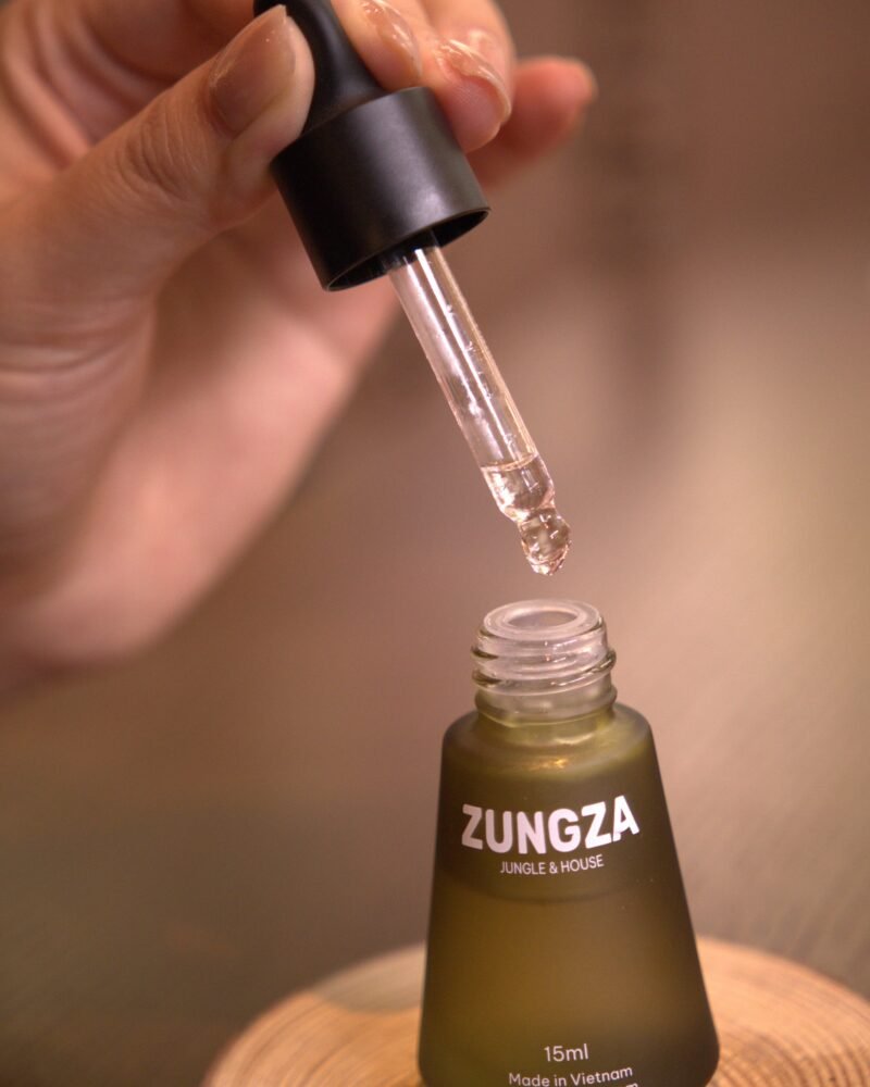 Chai tinh dầu ZUNGZA đặt giữa khung cảnh thiên nhiên - Tiêu đen, hoắc hương và bergamot trong một mùi hương